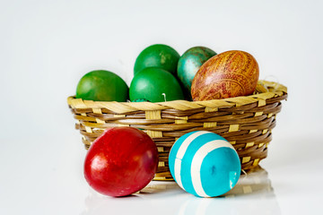 Closeup of basket with easter eggs on the white background. Eggs are painting in diferent  colors. Shallow dept of field. Easter concept.
