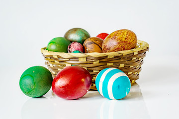 Closeup of basket with easter eggs on the white background. Eggs are painting in diferent  colors. Shallow dept of field. Easter concept.