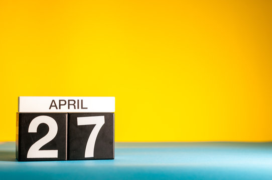 April 27th. Day 27 of april month, calendar on table with yellow background. Spring time, empty space for text
