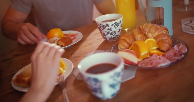 Young couple having breakfast together sitting around kitchen table