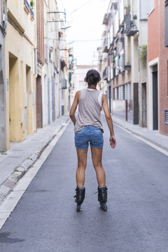 Rear view of teenage girl inline skating on road