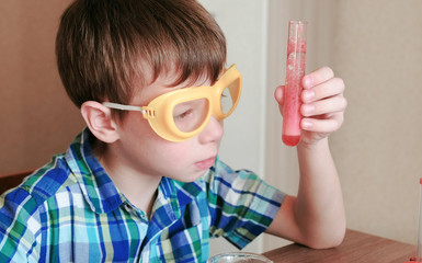 Experiments on chemistry at home. Boy looks at Chemical reaction with the release of gas in the...