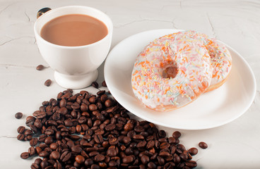 Donuts and coffee with natural milk on a light background. Junk food. Grains of aromatic coffee