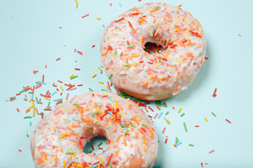 Donuts lie on a light turquoise background. Junk food