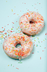 Donuts lie on a light turquoise background. Junk food