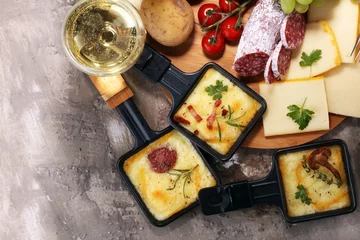Foto op Aluminium Delicious traditional Swiss melted raclette cheese on diced boiled or baked potato. © beats_