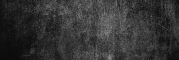 Textur einer fast schwarzen und alten Betonwand als Hintergrund, auf die leichtes Licht fällt