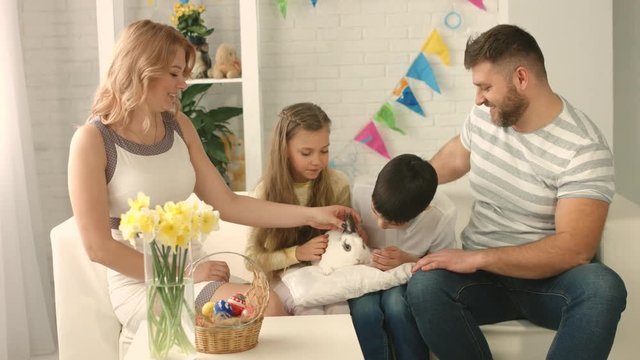 Happy family celebrating Easter and stroking a rabbit