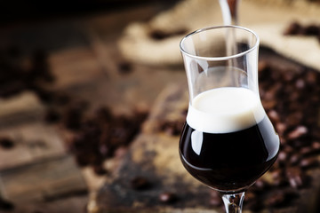 Two-layer cocktail with coffee liqueur, vintage wood background, selective focus