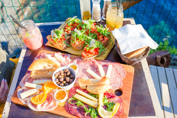 Tasty italian snack. Fresh bruschettes, cheeses and meat on the board in outdoor cafe with amazing view in Manarola, Italy