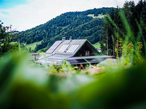 rustic wooden eco-friendly house with solar panels on the roof surrounded by green nature