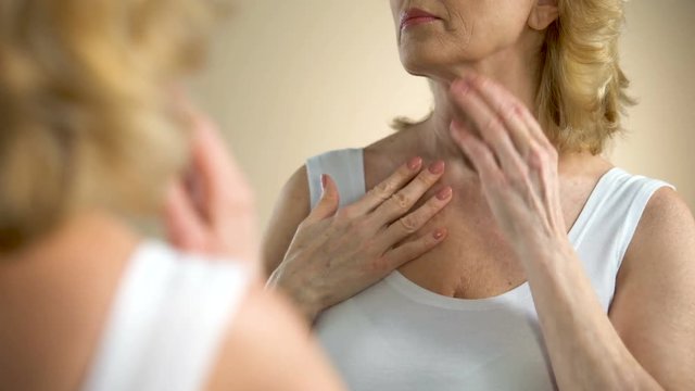 Senior woman looking at mirror reflection, aging process consequences, body care