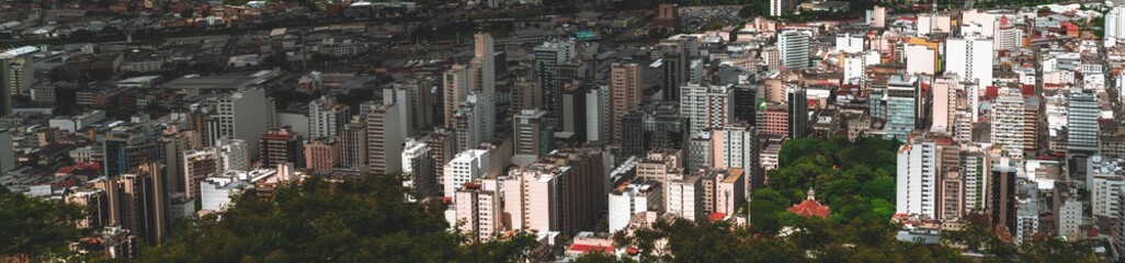 Fototapeta premium The panorama of Juiz de Fora city in Minas Gerais state of Brazil: plenty of multistorey building, parks, favelas, church, offices, and blocks of flats, chaotic mass scale, roads and streets