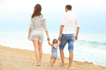 Couple with little daughter walking on beach