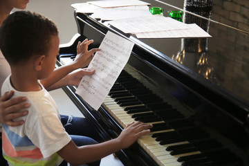 African-American boy with teacher learning to play piano indoors