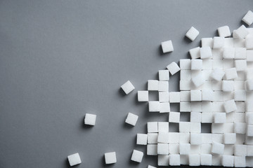 Refined sugar cubes on grey background, top view