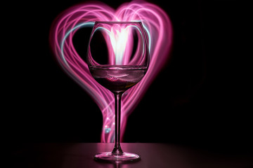 Wine glass on the table, in the background a pink heart