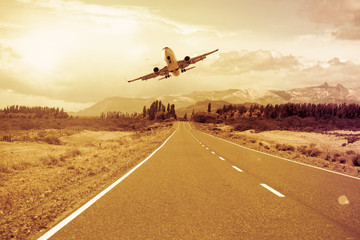 Fototapeta na wymiar Airplane flying over roadway