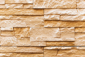 Wall of yellow and brown natural stone or sandstone. Texture of a part of an old decorative building.