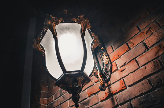 Fototapeta Big large forged vintage sconce lamp on a brick orange wall at night in the dark
