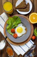 English Breakfast: fried egg, juice, cherry tomatoes, lettuce, grain bread, sauce, top view.