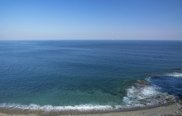 Fototapeta na wymiar Mighty rock, collapses in a blue sea, with sun glare, majestic rocks