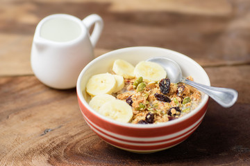 Muesli cereal with slice banana and milk in a bowl