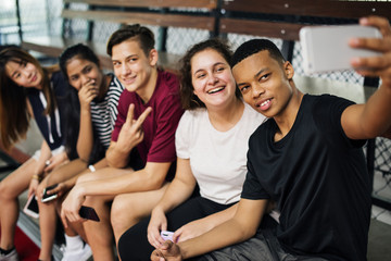 Group of young teenager friends on a basketball court relaxing taking a selfie