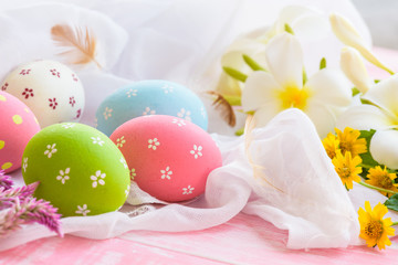 Happy easter! Colorful of Easter eggs in nest with flower,  paper star and Feather on white cheesecloth and bright pink pastel wooden background.
