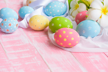 Happy easter! Colorful of Easter eggs in nest with flower,  paper star and Feather on white cheesecloth and bright pink pastel wooden background.