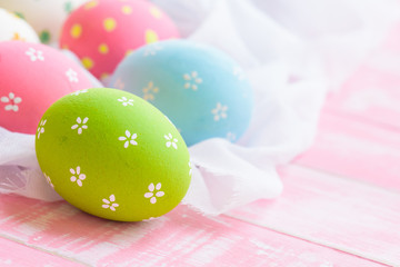 Happy easter! Colorful of Easter eggs in nest with flower,  paper star and Feather on white cheesecloth and bright pink pastel wooden background.
