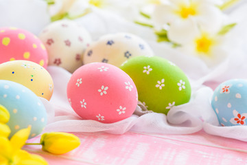 Fototapeta na wymiar Happy easter! Colorful of Easter eggs in nest with flower, paper star and Feather on white cheesecloth and bright pink pastel wooden background.