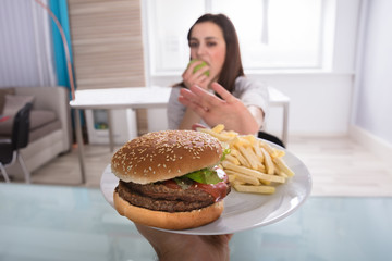 Woman Refusing Unhealthy Food While Eating Fruit