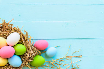 Colorful of Easter eggs in nest on pastel color bright blue and white wooden background.