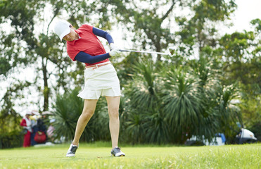 Obraz premium Asian woman playing golf swinging golf club for teeing off in course