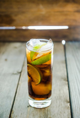 Cuba libre cocktail on the rustic background. Selective focus.