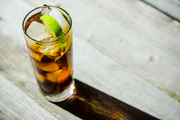 Cuba libre cocktail on the rustic background. Selective focus.