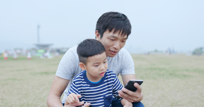 Father chatting with his son and using mobile phone