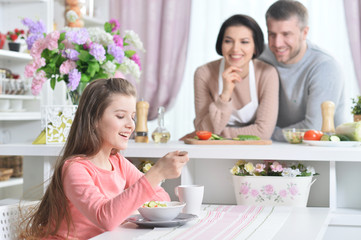 Obraz na płótnie Canvas Smiling girl eating at kitchen