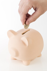 貯金箱に硬貨を入れる男性の手