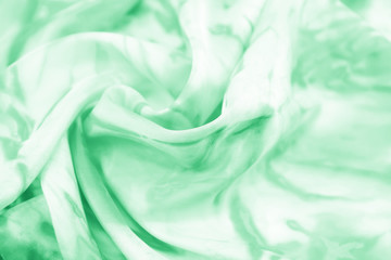 The texture of the satin fabric of green color for the background 