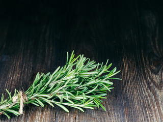 Organic bunch of fresh rosemary on wooden table with copy space. Low key