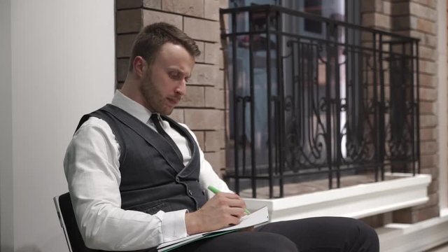 Businessman is writing something in his diary