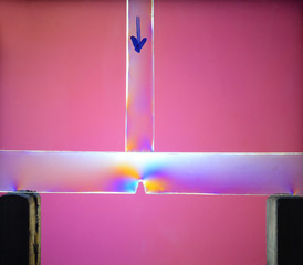 A force of 50 Newton is added from above (indicated by arrow) to a transparent balk. Polarized...