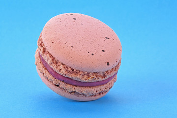 Tasty macaron on blue background. French cookie.