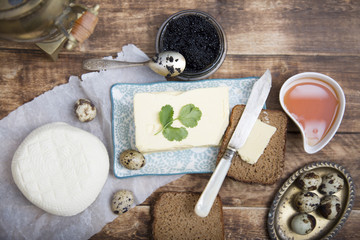 Breakfast table with bread slice, butter, black caviar, milk and honey 