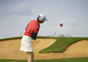 Asian woman playing golf outdoors in course in summer 
