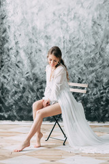 Fototapeta na wymiar Beautiful young bride in boudoir dress on canvas background with paint. Wedding trends and ideas 2018, spring inspiration. Wedding in the Studio