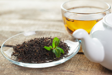 cup of black tea with mint leaves on a wooden table