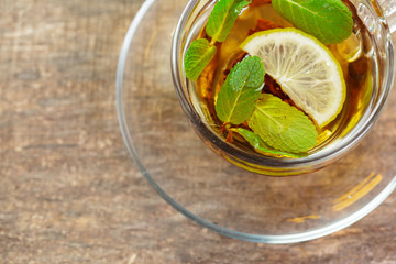 cup of black tea with mint leaves on a wooden table